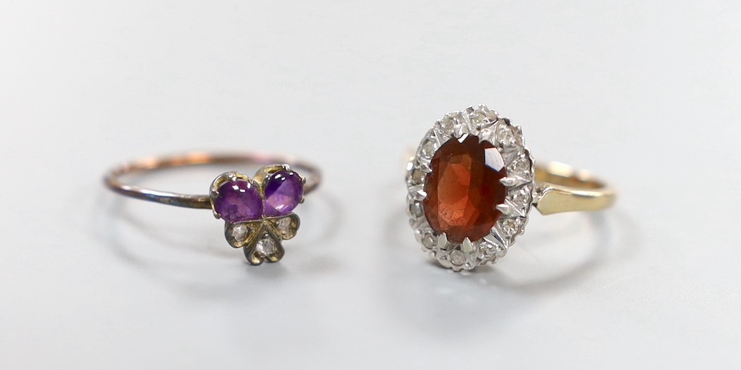 A continental yellow metal, garnet and diamond chip set oval cluster ring, size K and a small Victorian yellow metal, two stone cabochon amethyst and three stone rose cut diamond set cluster ring, size M, gross weight 4.